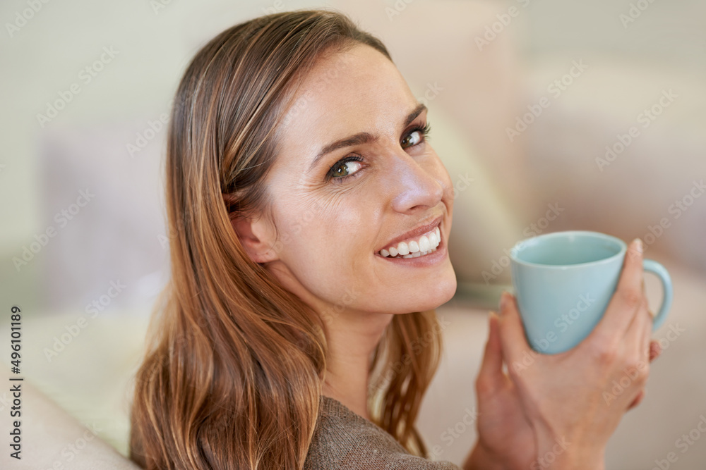 你想要一杯吗？一个漂亮女人坐在沙发上喝咖啡的肖像。