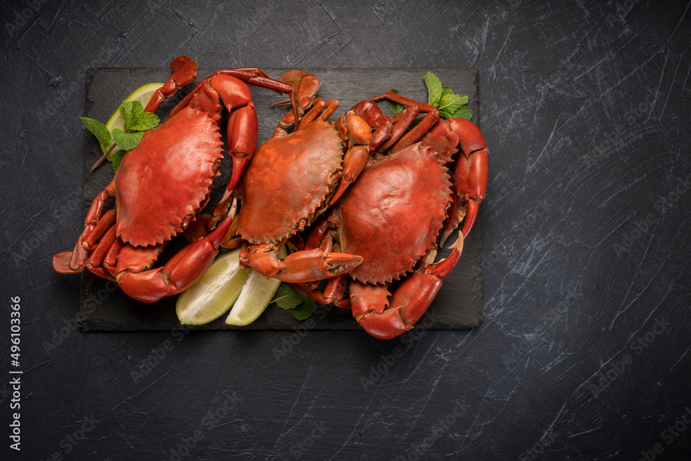 Steamed Red Crab with butter and lemon, Boiled Serrated mud crab on black plate on black background,