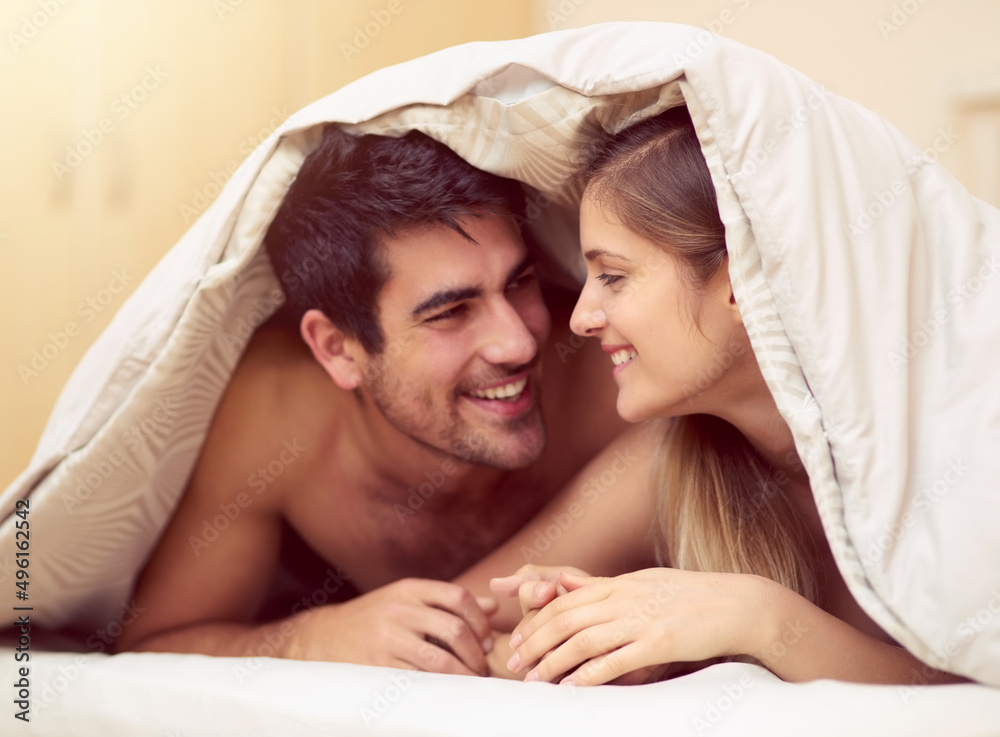 Love the one youre with. Shot of a loving young couple smiling at each other while lying under a bla