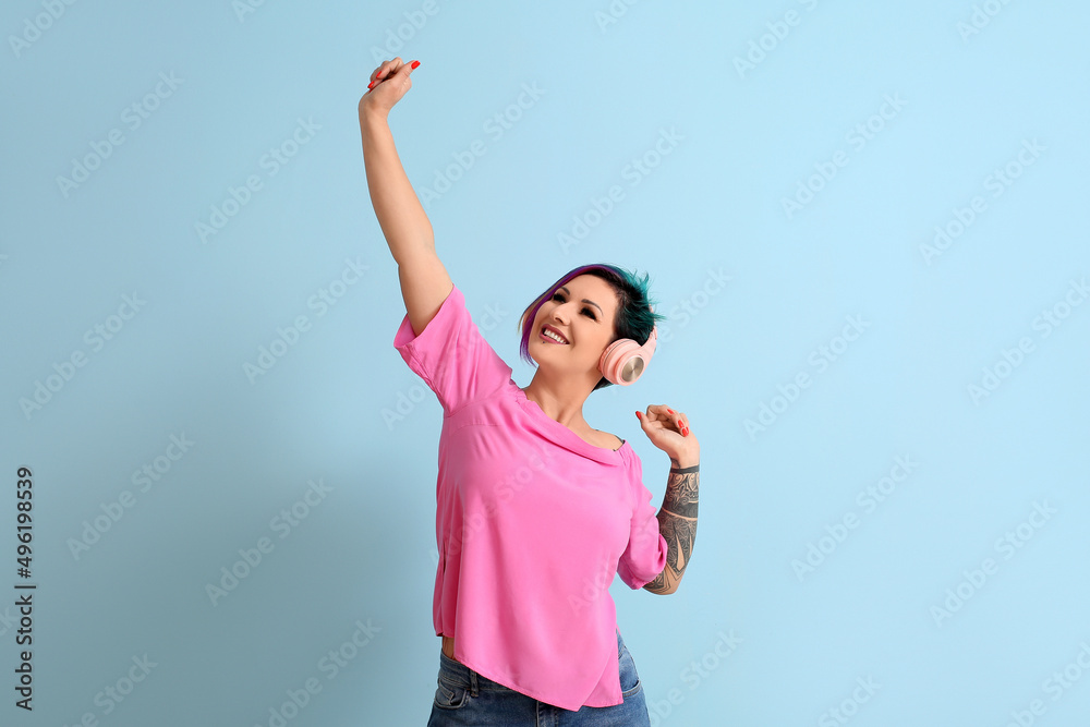 Beautiful woman with unusual hair listening to music on blue background