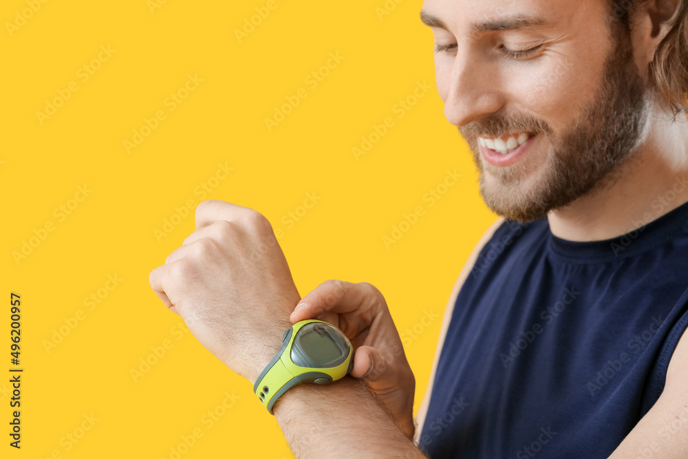 Sporty man with fitness tracker on color background