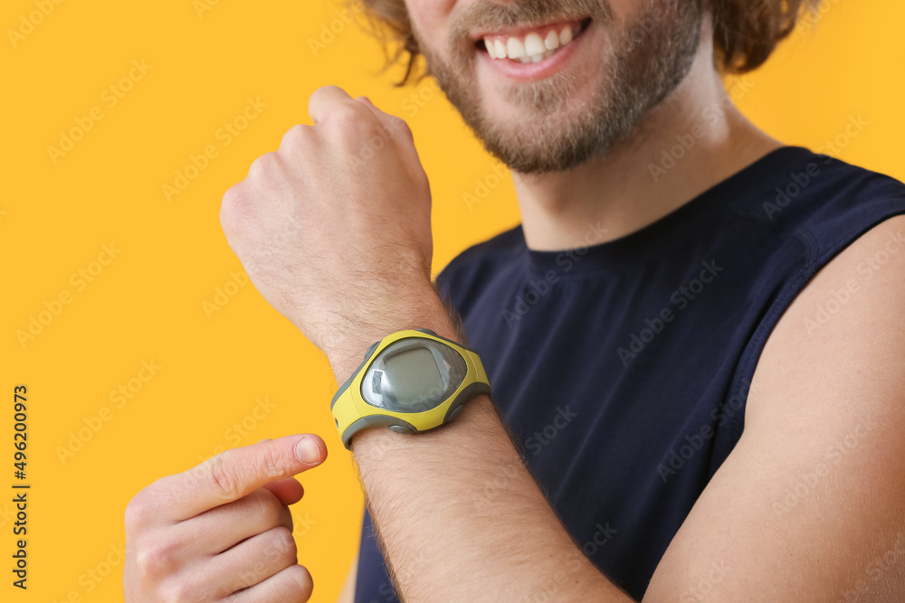 Sporty man with fitness tracker on color background, closeup