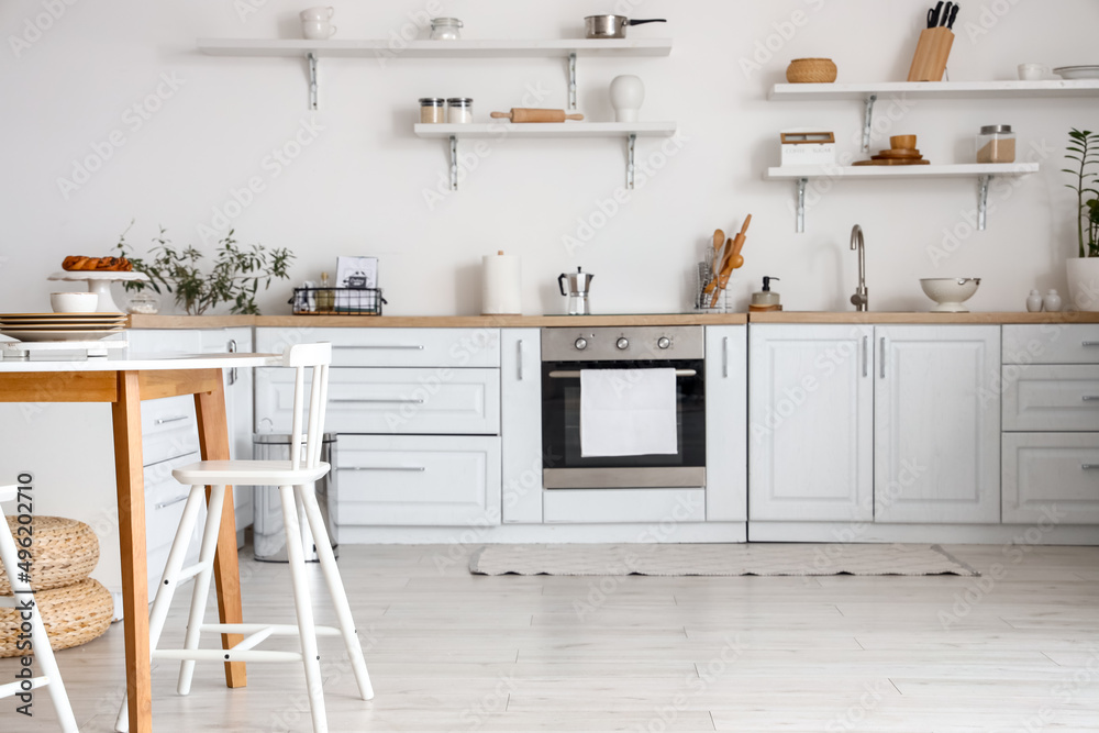 Interior of stylish kitchen with shelves and dining table