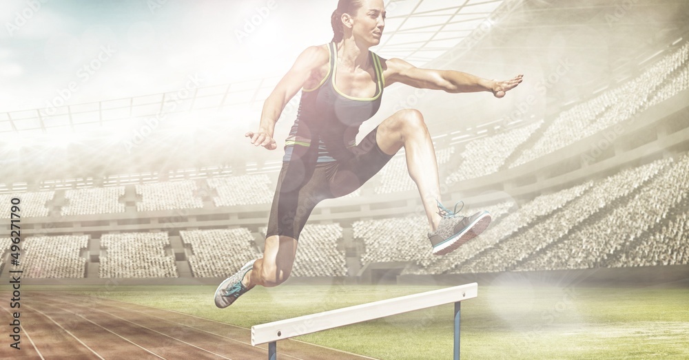 Spots of light against caucasian female athlete jumping over hurdles against sports stadium