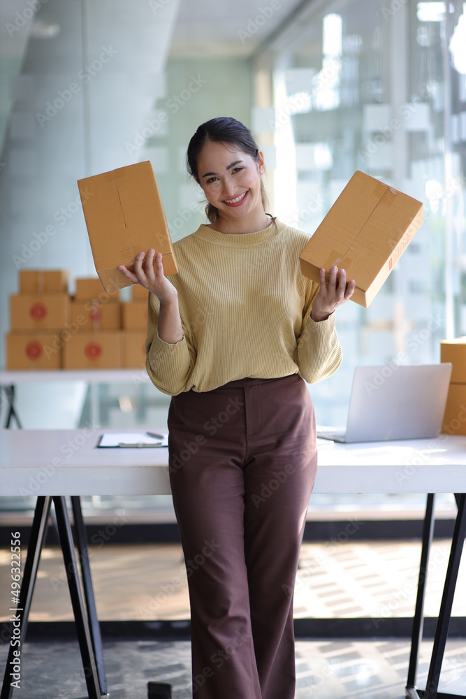 Portrait of a woman running an e-commerce startup in her home office while preparing parcels for del