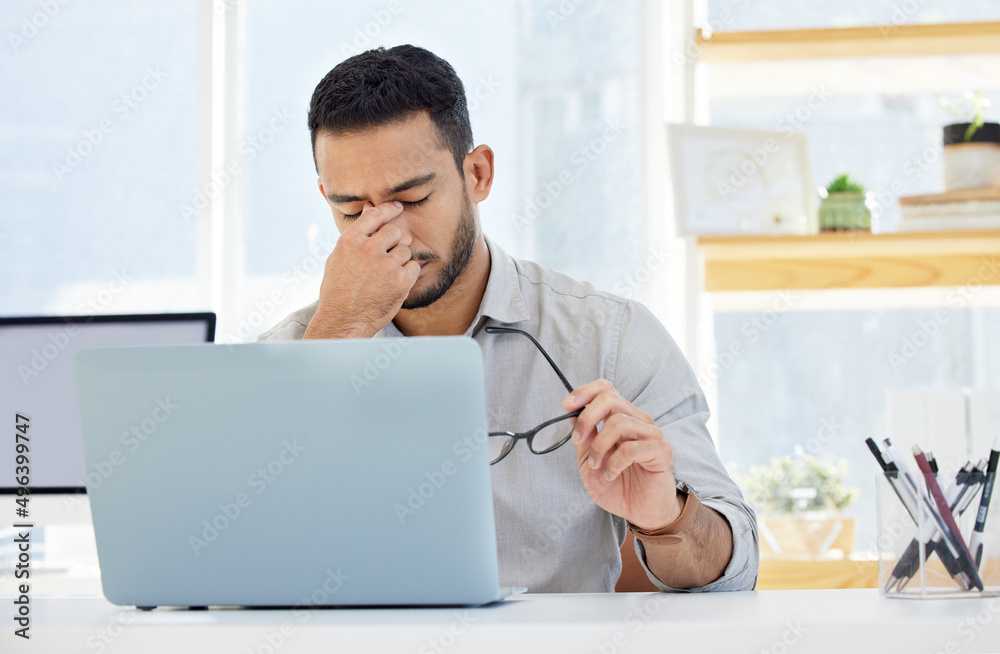 I think its time to take a break. Shot of a young man having a headache at work in a modern office.