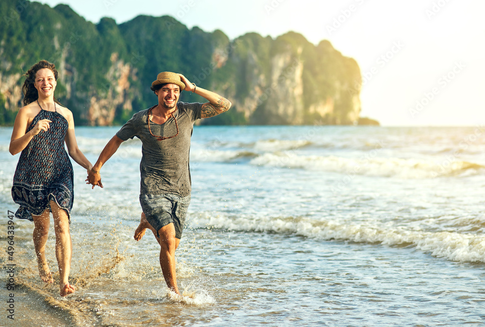 Getting our dose of vitamin sea. Shot of a happy young couple holding hands while running along the 