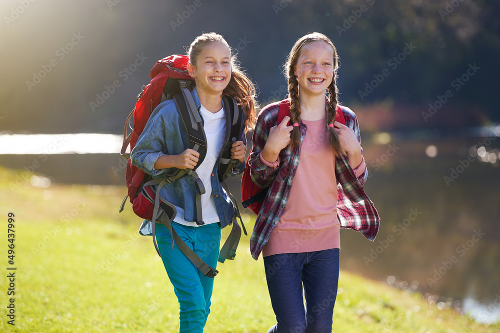 在一次女孩冒险中。两个年轻女孩背着背包在湖边散步的镜头。