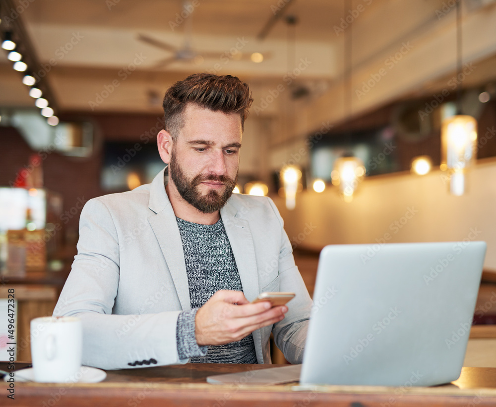 I should save this number.... Cropped shot of a modern businessman using his laptop and cellphone in