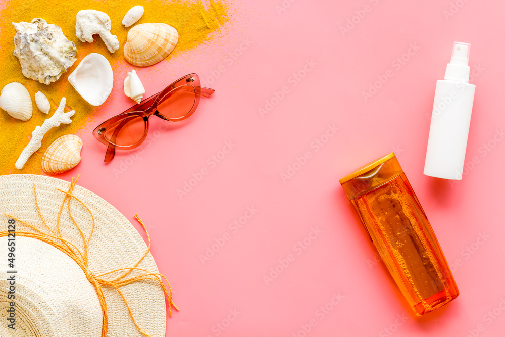 Beach sand and seashells with straw hat and bottles od sunscreen