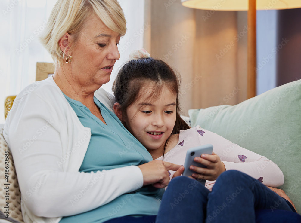 Can you download this game for me, gran. Shot of a little girl using a cellphone while sitting at ho