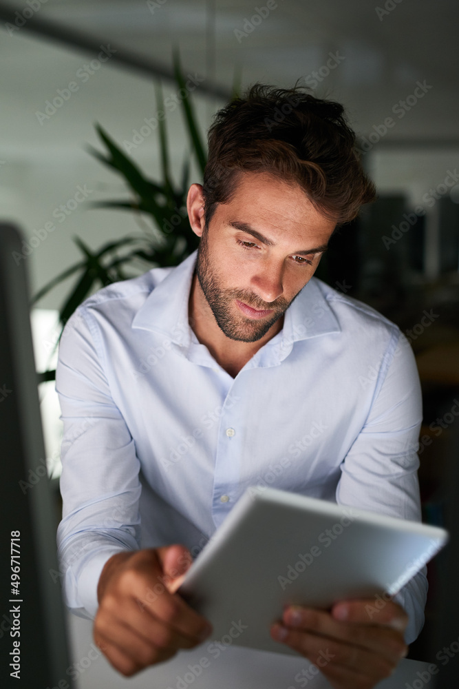 Putting in the hours to achieve success. Shot of a young businessman working late at the office.