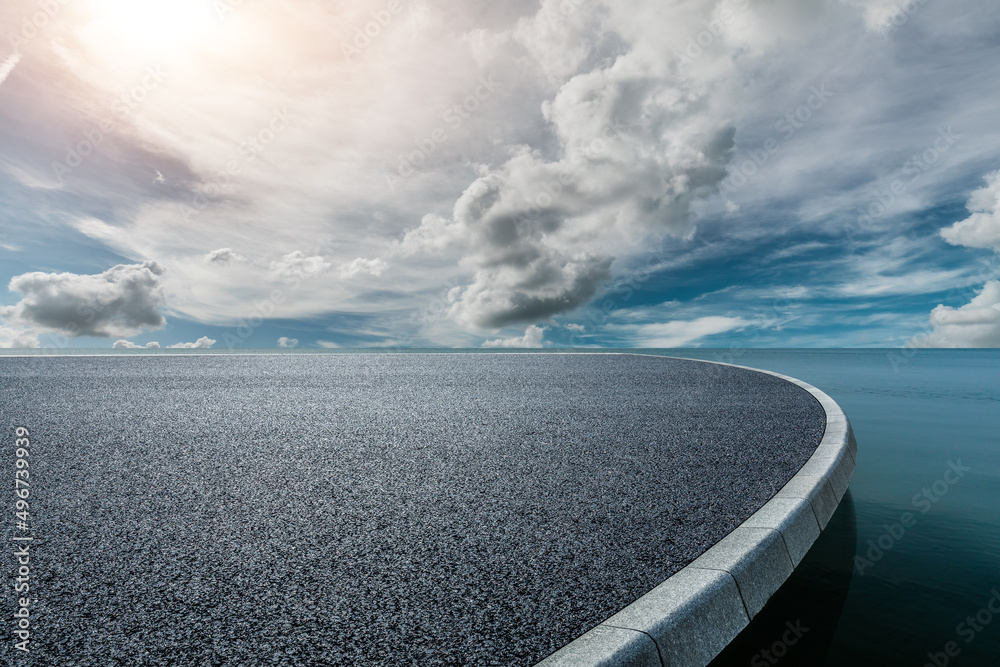 Round asphalt road platform near the lake under blue sky