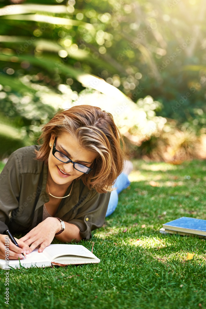 Putting it in her diary. Shot of an attractive young woman writing in her diary while outside on the