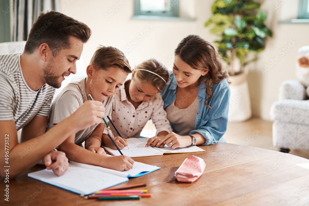 The family who learns together grows together. Shot of a happy young family of four doing homework t