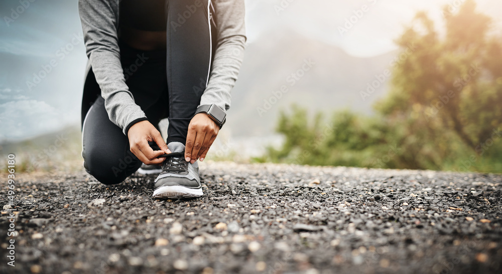 sporting the right footwear is an important factor. Closeup shot of a sporty woman tying her shoelac