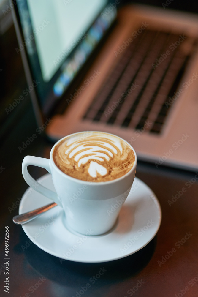 Freshly brewed to perfection. Still life shot of a cup of coffee and a laptop on a table.