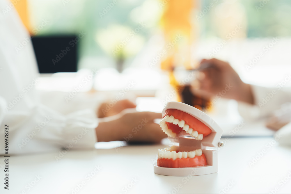 Close up dentist holding teeth model denture and explorer mirror tool for showing and explaining to 