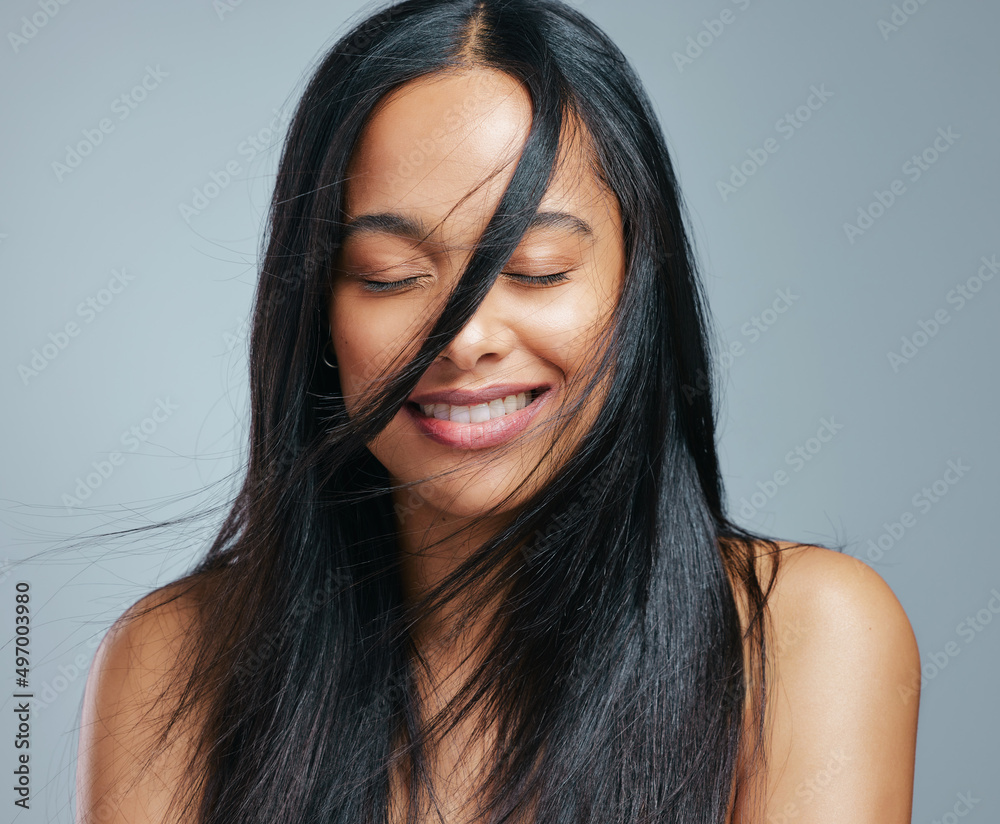 Check out her natural shine. Studio shot of an attractive young woman posing against a grey backgrou