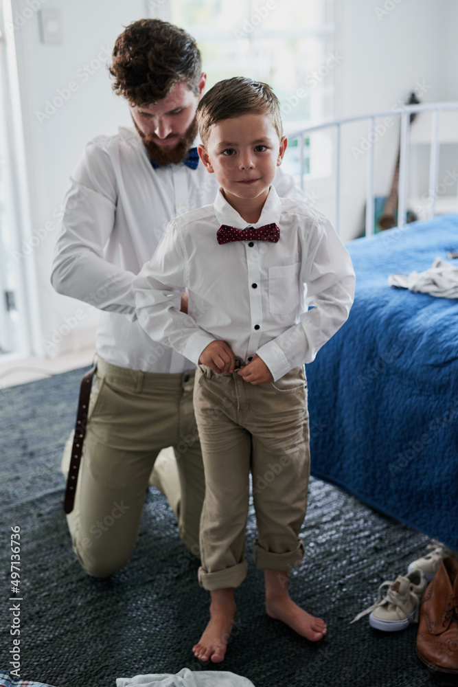 Almost done and ready to go. Shot of an adorable little boy and his father getting dressed in matchi