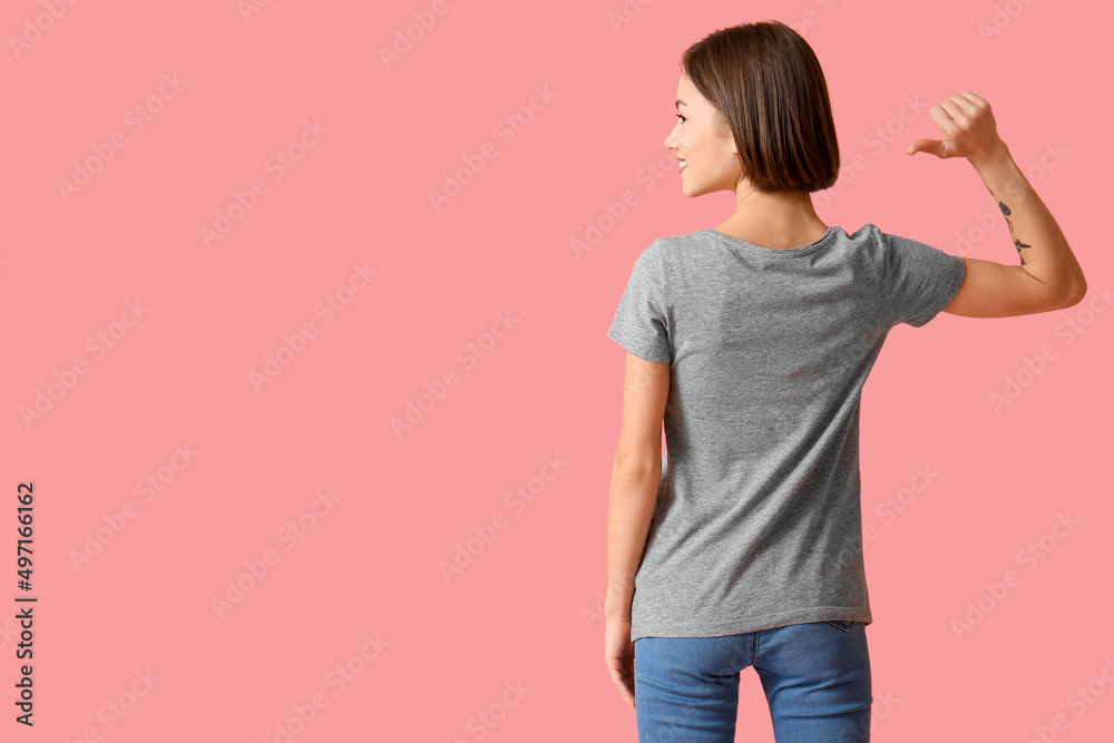 Beautiful young woman in stylish t-shirt on color background, back view