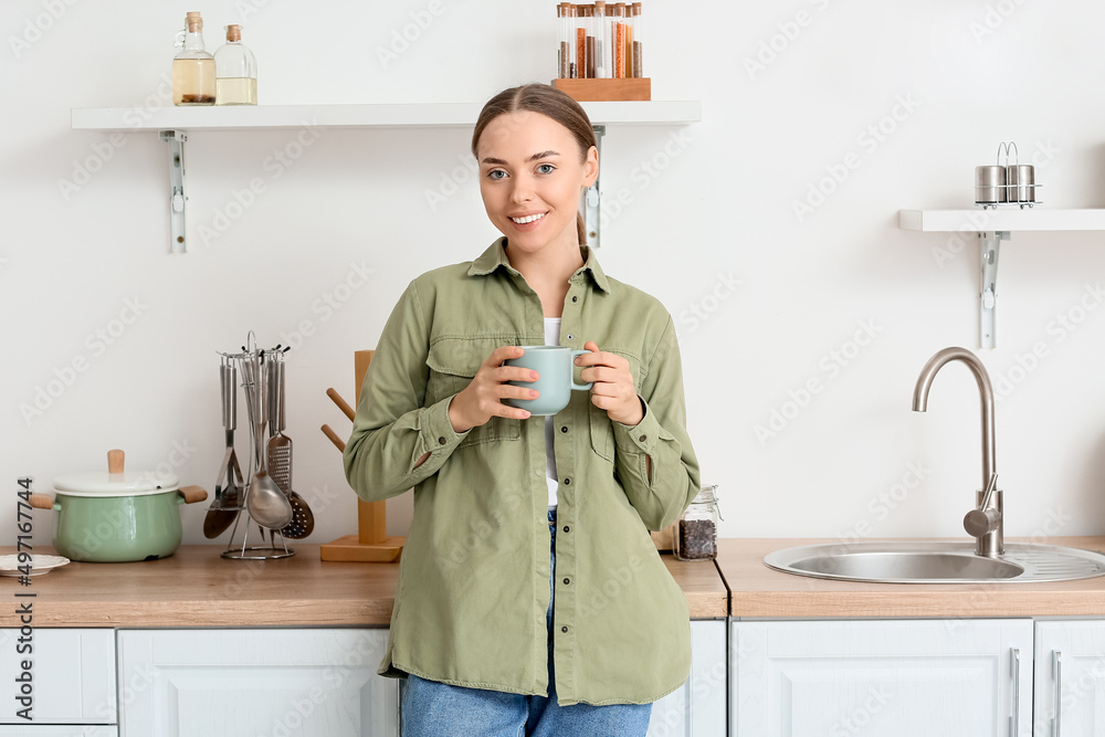 厨房里喝着一杯美味咖啡的年轻女人