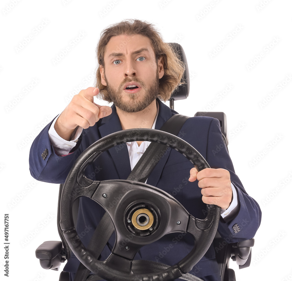 Stressed businessman in car seat and with steering wheel pointing at viewer against white background