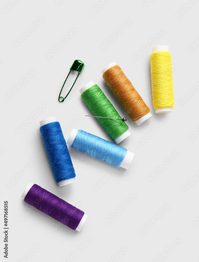 Thread spools with needle and pin on white background