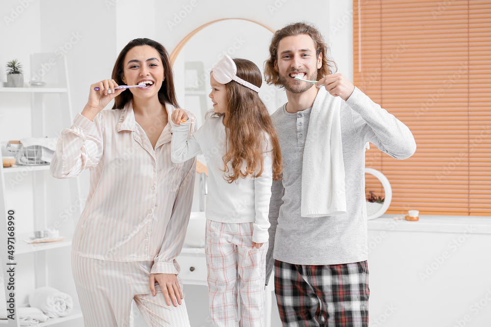 Little girl with her parents brushing teeth in bathroom