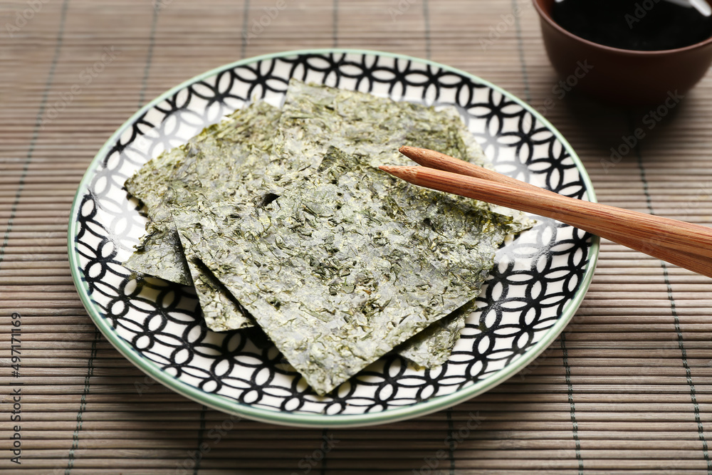 Plate with tasty seaweed sheets on bamboo mat