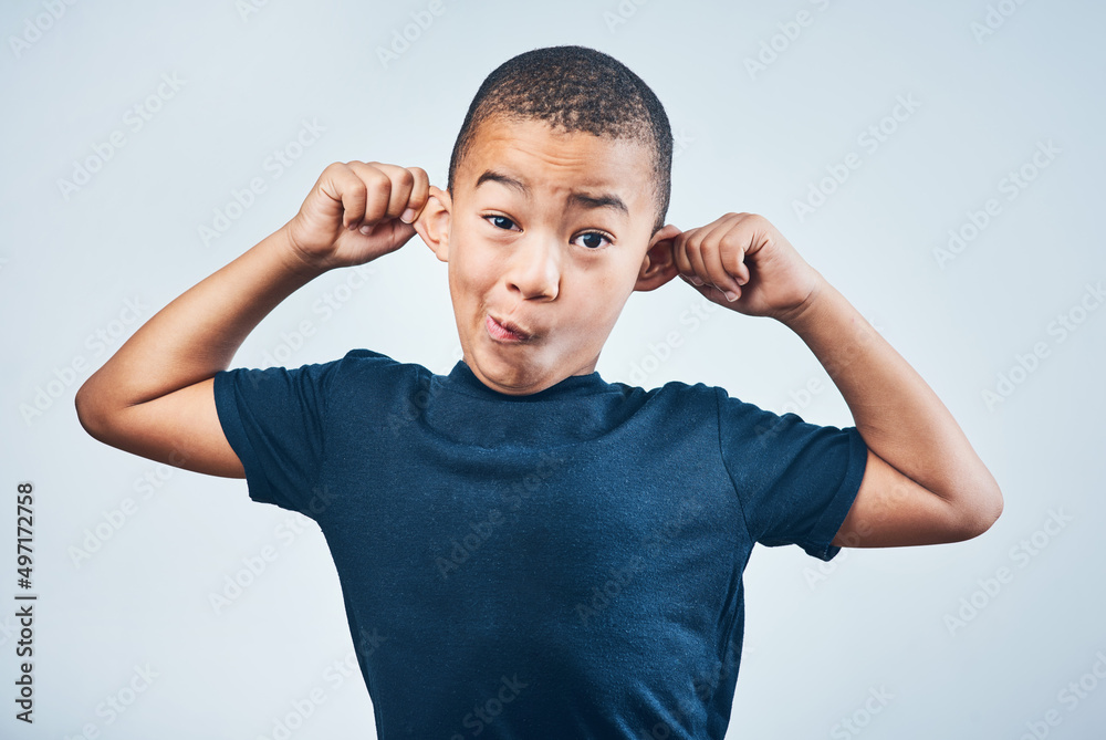 Goofy Ill show you goofy. Studio shot of a cute little boy playfully pulling his ears against a grey