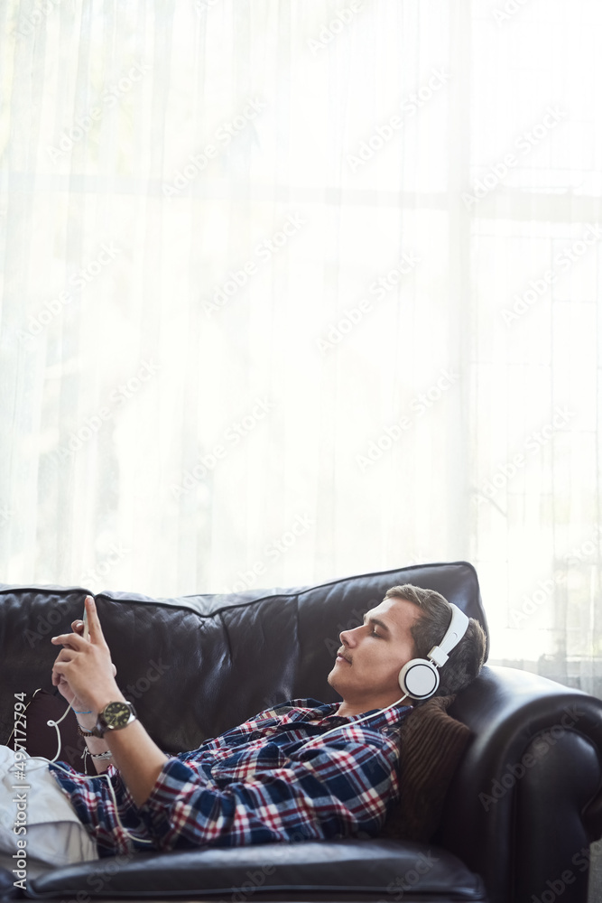 Chilling out with some fresh tunes. Shot of a young man surfing the net at home.