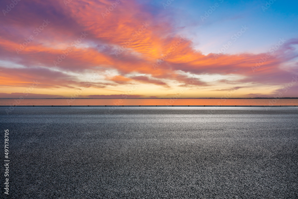 Empty asphalt road and lake with beautiful sky clouds at sunset