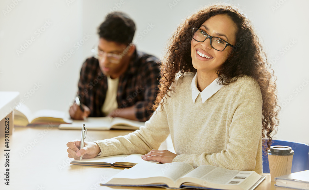 做笔记。一位年轻漂亮的女大学生在笔记本上写字的裁剪肖像