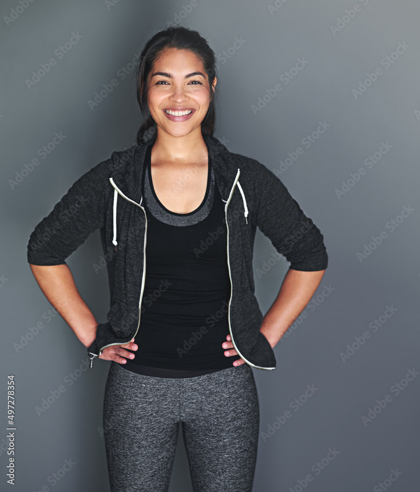 In shape and feeling great. Portrait of a fit young woman in sports clothing posing against a gray b