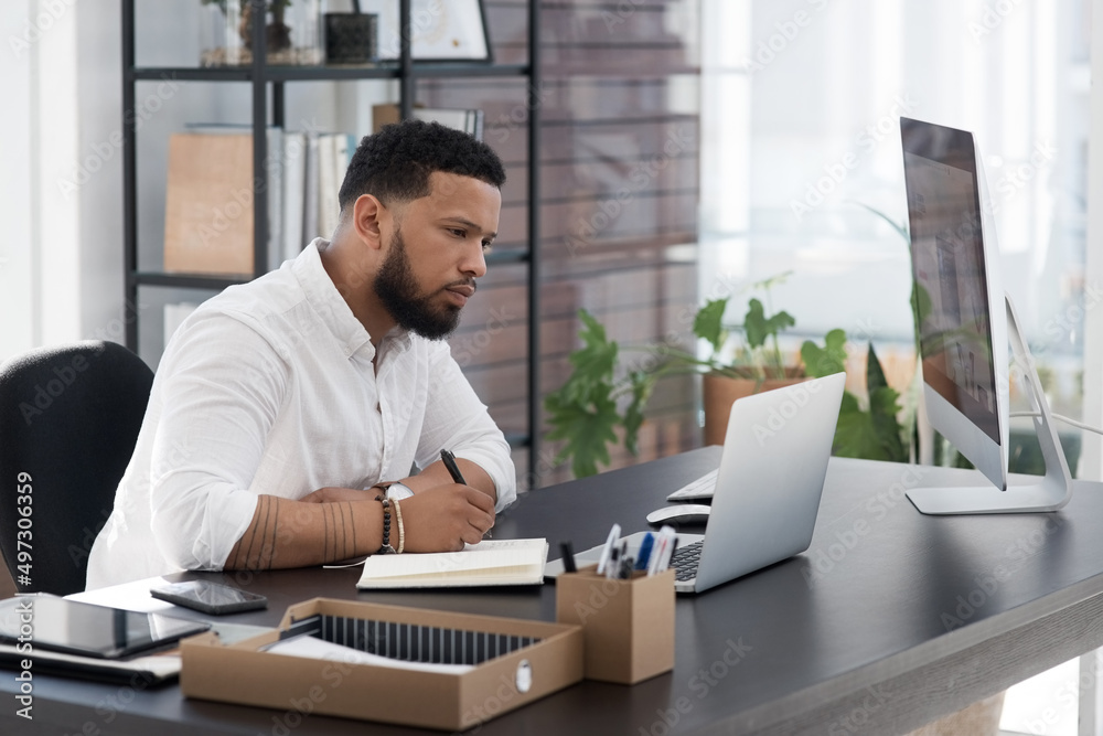 Sitting down for some thorough planning. Shot of a young businessman writing notes while working on 