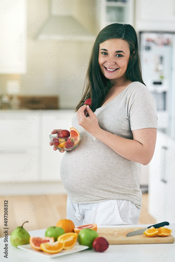 健康的饮食等于健康的婴儿。一位孕妇在厨房里做水果沙拉的照片。