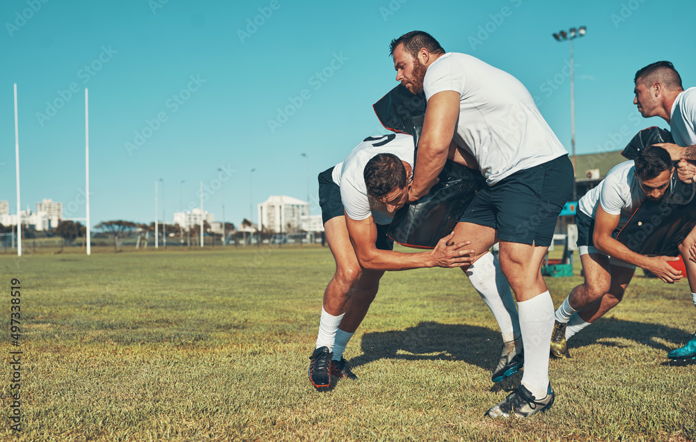 Mastering the basics of safe and effective tackling. Shot of rugby players training with tackle bags