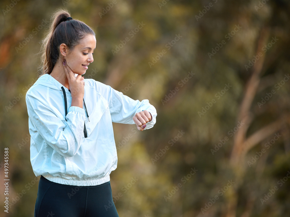 Lets see how fit I really am. Shot of a sporty young woman checking her pulse while exercising outdo