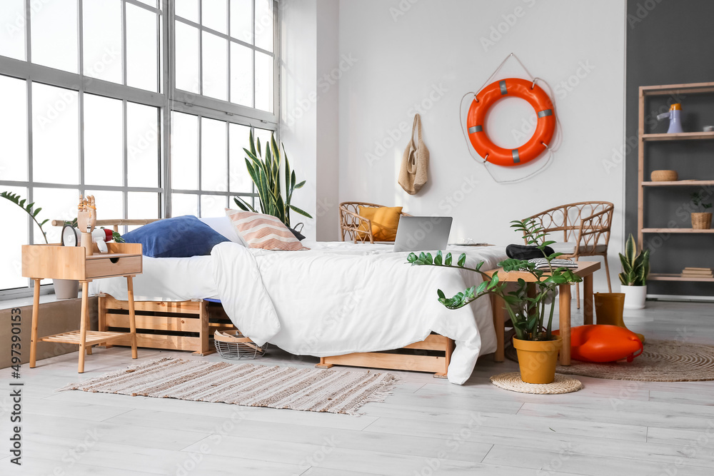 Interior of light bedroom with ring buoy and houseplants