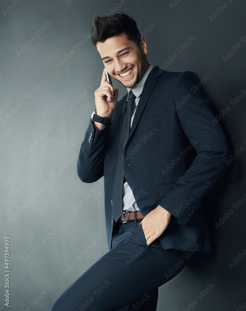 Talking in style. Studio shot of a young businessman talking on a cellphone against a gray backgroun