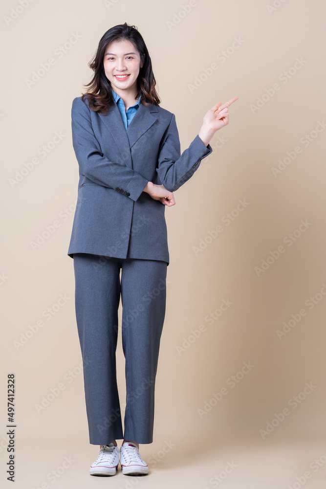 Full length image of young Asian business woman on background