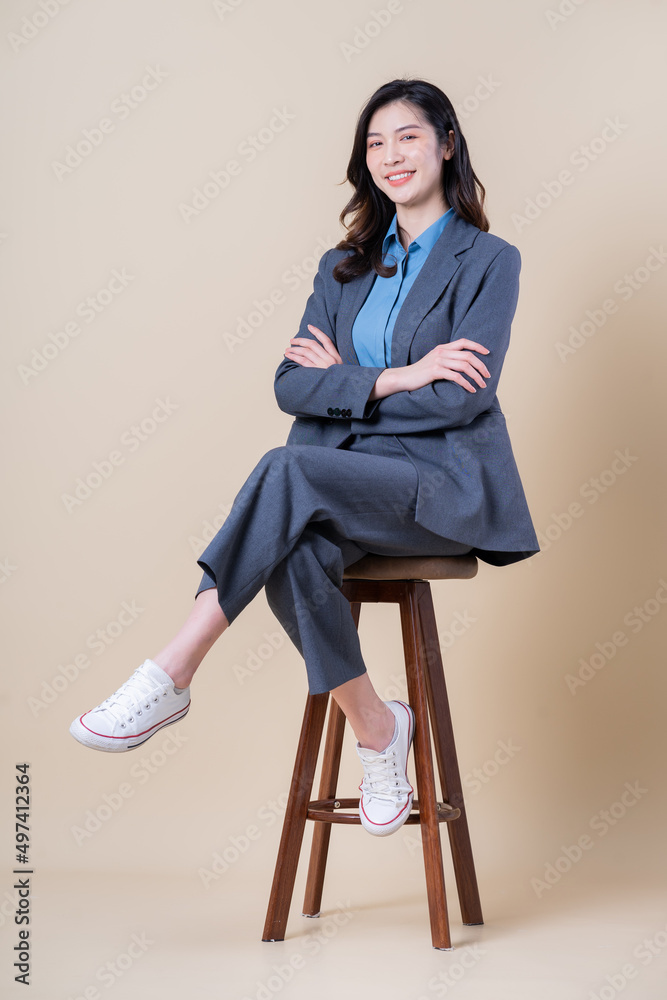 Full length image of young Asian business woman on background