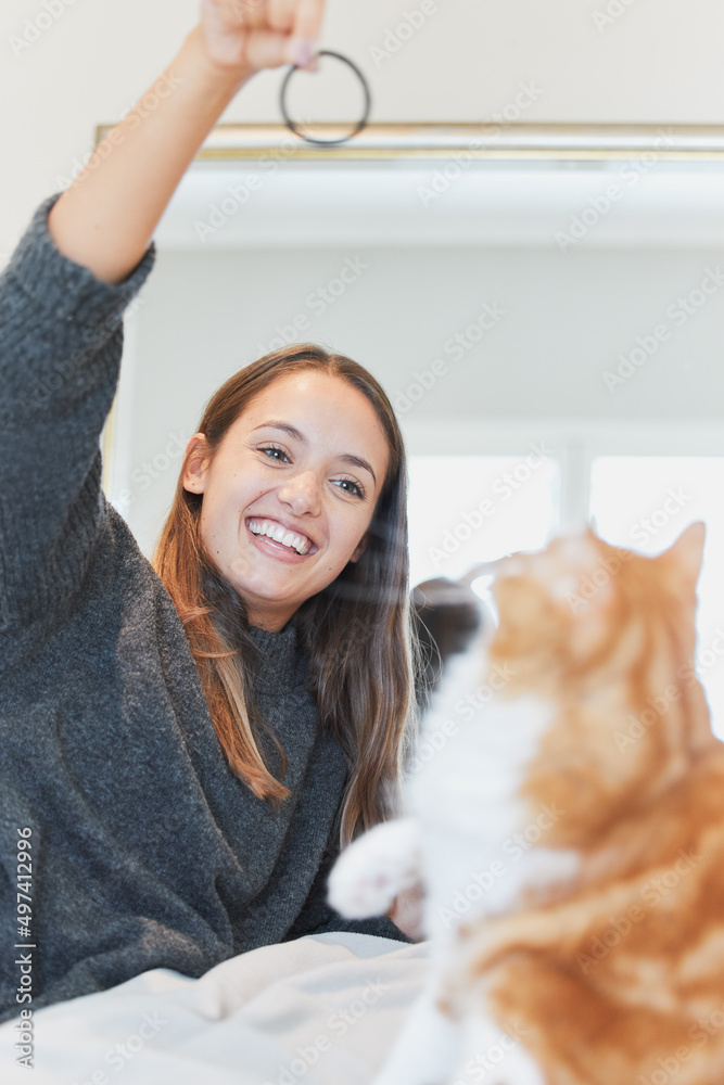 和我的猫一起玩让我心情最好。一个年轻女人在家和她的猫一起玩的照片。