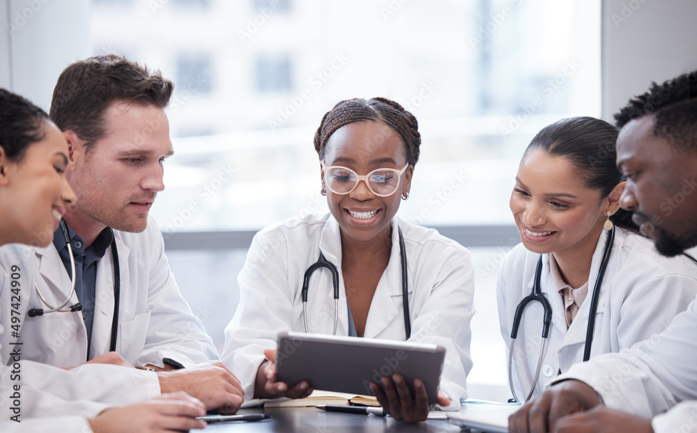 Take a look at this. Cropped shot of a group of young doctors looking at a tablet during a meeting i