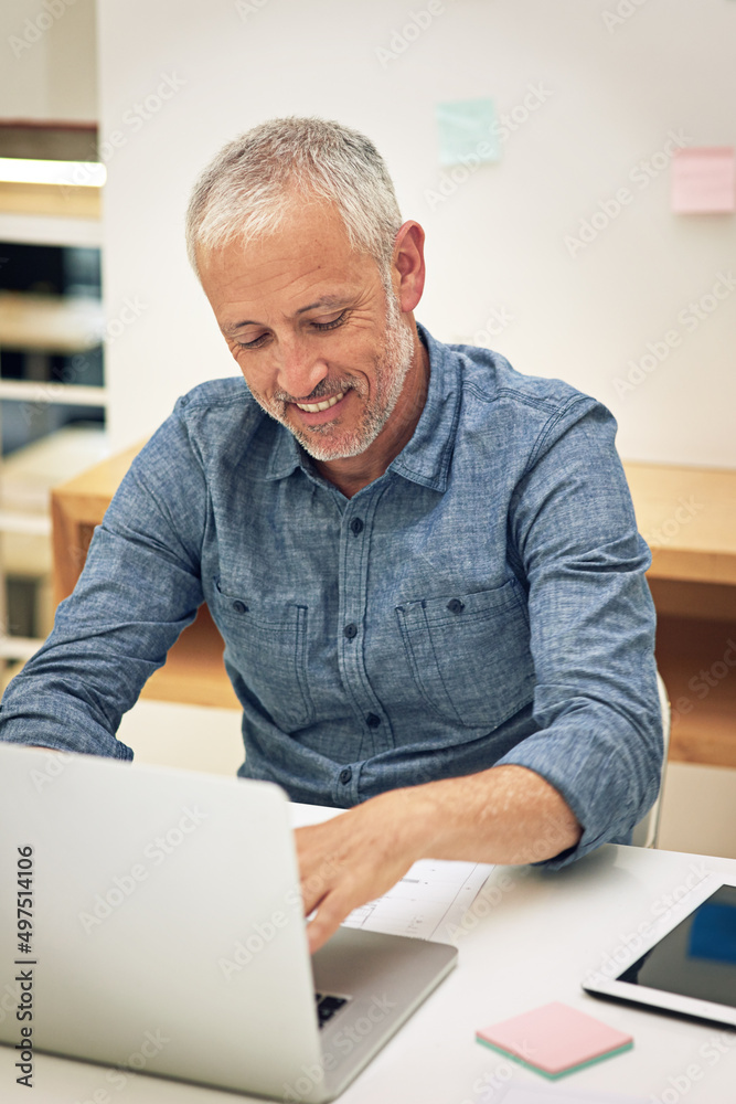 Work is a breeze with wireless technology. Shot of a businessman using a laptop at his desk in a mod