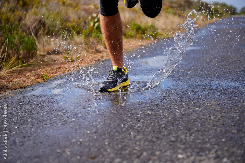 Cross country training. Cropped shot of a young man running on a country road.