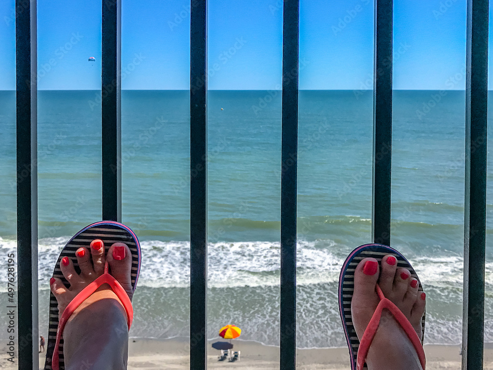 two female feet with a pedicure against the background of the ocean beachfront boardwalk Myrtle Beac