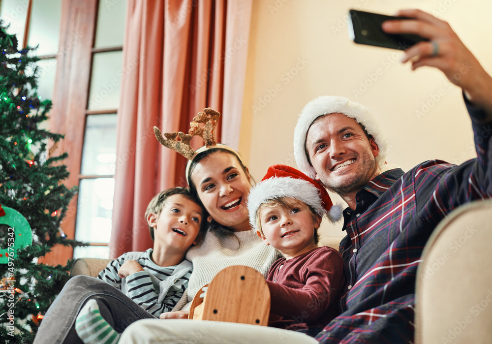 Its Christmas, time to enjoy yourselfies. Shot of a happy young family of four taking selfies during