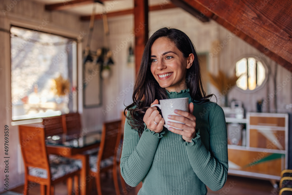 Close up of a woman holding a cup of coffee, looking through the